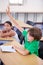 Child raise his hand in school for questions, support and help with classroom education and teaching in school