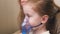 The child is receiving respiratory therapy with a nebulizer. Mommy inhales a little girl in a mask with a nebulizer at