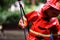 Child with red raincoat of firefighter clings to a rope in a playground during rain
