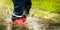 Child with red rubber boots jump in puddle on rainy autumn day. waterproof clothing. copy space