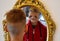 The child reflected in a distorting mirror. A fun reflection of the boy. Children`s entertainment