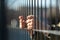 Child refugee hand holding a metal fence