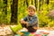 Child relax in autumn forest. Forest school is outdoor education. Visit natural spaces. Boy in rubber boots relaxing in