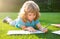 Child relax in the holiday. Kid with pencil writing on notebook on grass background.