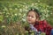 A child rests in a field with a wreath of field daisies