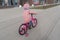 A child rides a bicycle in a pink jacket. A child with his back to the photographer. Spring walks near the house on the