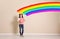 Child with roller brush near color wall.