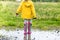 A child in rubber boots jumps in a puddle