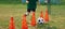 Child running soccer ball between training cones. European football sports summer camp for junior level athletes