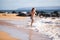 Child running through water close to shore along the sea beach. A boy runs along the sea coast. Rest of children on