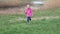 A child runs on fresh grass with an apple in his hand. In the background there is a lake with a duck