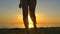 Child runs after his mother on the beach near the sunset.