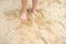 Child`s bare feet in the sand, boy plays in the summer with sand on the playground, in the sandbox, the concept of building sand