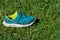 Child`s blue and green shoe sits in the sunshine on the green grass prepared for activity and sports in the summer