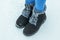 The child`s feet in jeans and warm boots on the snow.