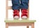 Child\'s feet standing on the little chair on tiptoes
