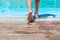 the child`s feet step on the grate near the edge of the pool and the child prepares to enter the water.