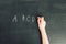 Child`s hand with chalk write alphabet on black chalkboard