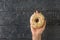 A child\\\'s hand with a fresh doughnut on a wooden table