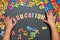 Child`s hand laid out the word education from multicolored plastic letters