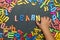 Child`s hand laid out the word learn from multicolored plastic letters