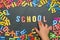 Child`s hand laid out the word school from multicolored plastic letters