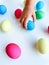 Child& x27;s hand picking up a blue Easter egg among colorful eggs on a white surface, interactive and engaging holiday