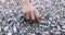 A child's hand picks up and pours out sea pebbles