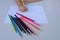 The child`s hand preparing to write on a white sheet of paper with colored pencils.  Education and children activities concept