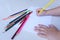 The child`s hand preparing to write on a white sheet of paper with colored pencils.  Education and children activities concept