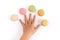 Child`s hand spreading fingers with five macarons.