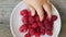 Child`s hand taking some fresh juicy raspberries