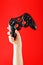 A child`s hand triumphantly holds the gamepad on a red background