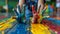 A child& x27;s hands covered in paint on a colorful floor, AI