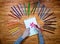 Child`s hands drawing a flower on a notebook with color pencils on the wooden table