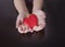 Child`s hands holding the heart on the wooden background. The concept of caring, family, protection, love, health