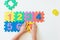 Child`s hands playing with numbers, learning simple multiplication. Colorful bright puzzle numbers on white background, education