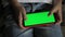 Child`s hands press on the green screen of the smartphone in the window. Chromakey. Mock up. Horizontal position