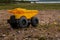 A child`s yellow dump truck abandoned on the ground by a lake, side on view