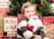 Child with santa doll in front of christmas tree