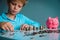 Child saving money, boy put coins into piggy bank