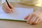 Child, schoolboy in yellow t-shirt, writes letters in notebook with an pencil, bright backlight, education concept, elementary