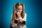 Child schoolgirl reading a book on blue background