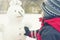 A child sculpts a snowman in the winter on the street, a boy in a red overall