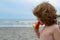 Child on the sea with watermelon. Summer taste. Cheerful kid holding slice of watermelon while standing outdoors on