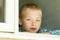 Child with serious expression sitting near window