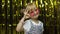 Child show ok sign, smiling, looking at camera. Girl posing on background with foil golden curtain