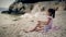 Child sits on the beach of the Adriatic Sea and throwing stones into the water.