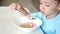 The child sits at the kitchen table and eats soup close-up. The concept of healthy baby food.