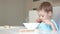 The child sits at the kitchen table and eats soup. The concept of healthy baby food. Camera slider movement.
